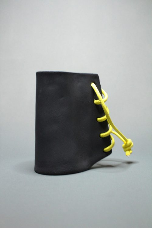 Sculpture haute couture n°3. Grès noir et lacet jaune.